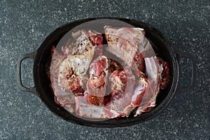 Seasoned lamb meat in black iron pot, top view