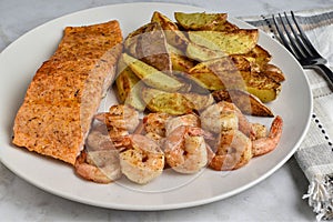 seasoned salmon served with shrimp and potato wedges photo
