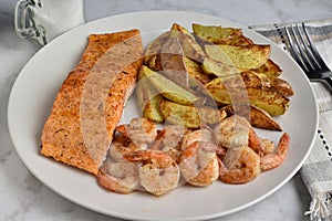seasoned salmon served with shrimp and potato wedges photo