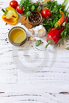 Seasoning background. Fresh and dry herbs, spices, olive oil and vegetables on a wooden table.