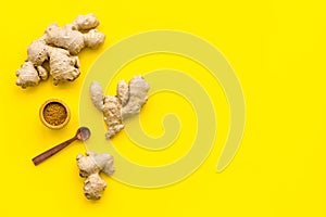 Seasoning. Ground ginger in small bowl near ginger root on yellow background top view copy space