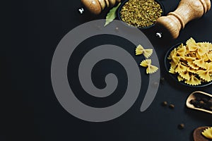 Seasonings, herbs and pasta on black background