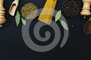 Seasonings, herbs and pasta on black background