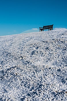 Seat on Cleeve Hill skylined on a bright snowy winters day, Cotswolds, Gloucester UK photo
