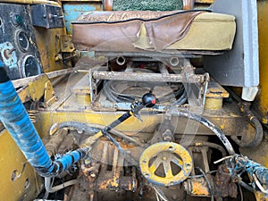 Seat, levers and controls of a yellow old road roller for asphalt paving and road repairs on a construction site. Construction