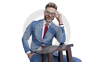 Seated attractive businessman sticking one hand in pocket