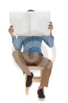 Seated attractive man covering his face with a newspaper