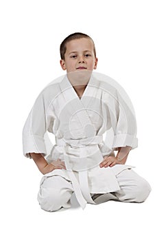 Seated boy in judo kimono on white