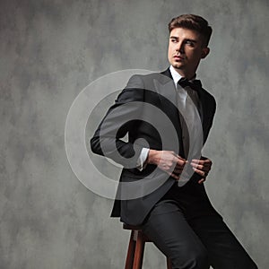 Seated businessman buttoning his suit and looking to side