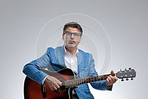 Seated businessman playing his guitar and singing serious