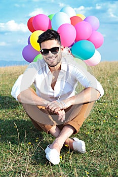 Seated casual man with balloons and sunglasses