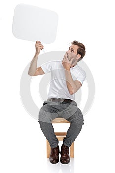 Seated casual man is shocked when looking to speech bubble