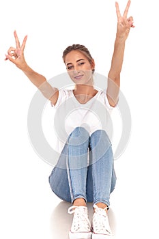 Seated casual woman making victory sign