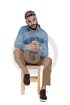 Seated charmed man looking away while rubbing his palms