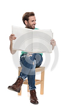 Seated cool guy looking away with newspaper in hands