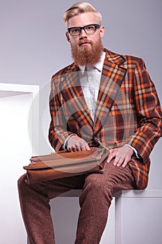 Seated fashion man with long beard and briefcase