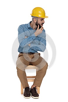 Seated fashion man thinking with folded arms while looking careful