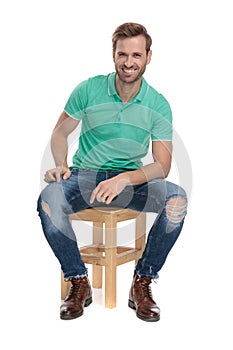 Seated happy man resting his arm on leg