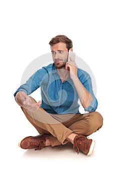 Seated man is having a confusing discussion on the phone