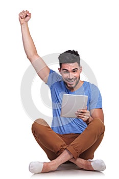 Seated man with tablet pad celebrating success