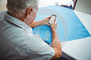 seated retired man looking at his smartphone