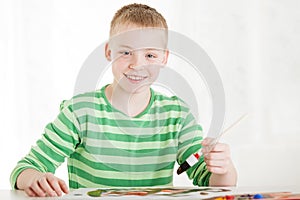 Seated smiling boy holds brush in hand
