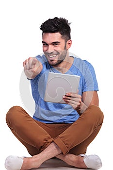 Seated smiling man with tablet pad is pointing