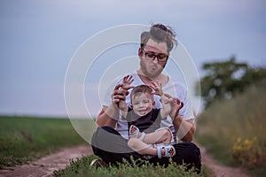 Seated on tranquil path, young, diversity father with happy son on lap, both enjoying atmosphere