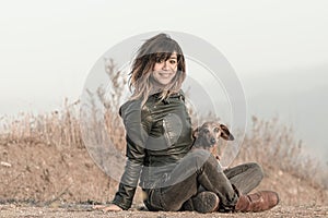 Seated woman with leather jacket and Dachshund