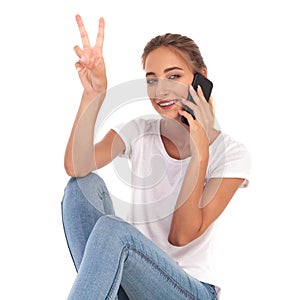 Seated woman talking on the phone makes the victory sign