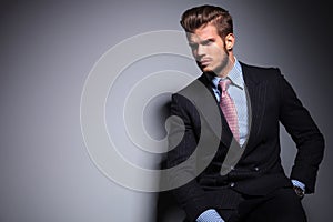 Seated young fashion model in suit looks away