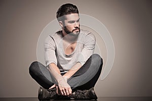 Seated young man with beard looks away