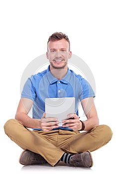 Seated young man holds his tablet