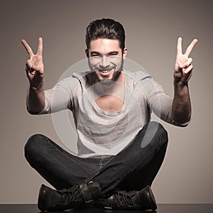 Seated young man making the victory hand sign