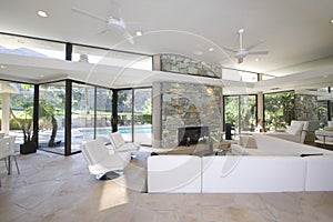 Seating Area And Stone Fireplace In Spacious Living Room With Pool View
