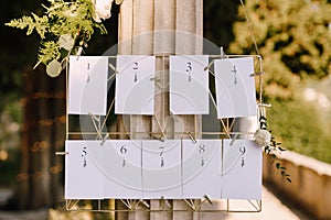 Seating plan. Numbered blank cards on a metal wicker stand hang on a column. Inscription: 1, 2, 3, 4, 5, 6, 7, 8, 9