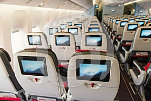 Seats on board of airplane. Economy class with screens