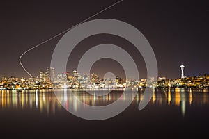 Seattle skyline by night with airplane trail