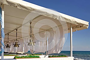 Seaview Restaurant Exterior. White Terrace With Wooden Furniture