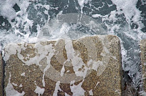 Seawater pours off of stones of breakwater as the wave recedes, Ogden Point, Victoria, BC. photo