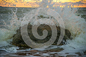 Seawaves during sunset. Big stone in water. Waves crashing to stone. Colorful evening sky. Wonderful Baltic seaside in Karkle.