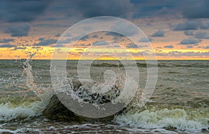 Seawaves during sunset. Big stone in water. Waves crashing to stone. Colorful evening sky. Wonderful Baltic seaside in Karkle.