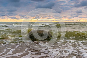 Seawaves during sunset. Big stone in water. Waves crashing to stone. Colorful evening sky. Wonderful Baltic seaside in Karkle. photo