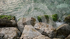 Seaweed and algae covered rocks being washed by sea waves in slow motion. Perfect as a marine background.