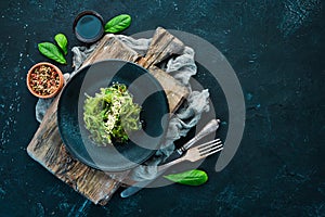 Seaweed salad in a black plate. Chuka wakame On the old background.