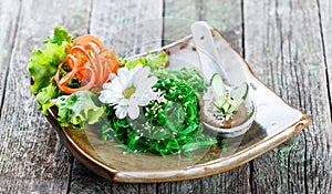 Seaweed Salad wakame in plate with chopsticks on bamboo mat. Japanese Cuisine - healthy sea food.