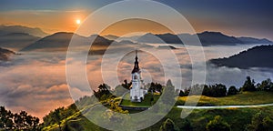 Sebrelje, Slovenia - Aerial panoramic drone view of the beautiful hilltop church of St.Ivan Sv. Ivan Cerkev at sunrise with fog photo