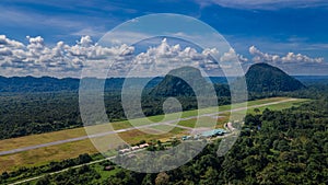 Secluded airport at Mulu village with road, tropical forest and mountains near Gunung Mulu national park. Borneo. Sarawak.