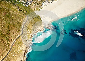 Secluded beach. Aerial shot of a road running along a rugged coastline to a sandy beach.