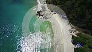 secluded beach with powdery white sand. Lush green palm trees line the shore.